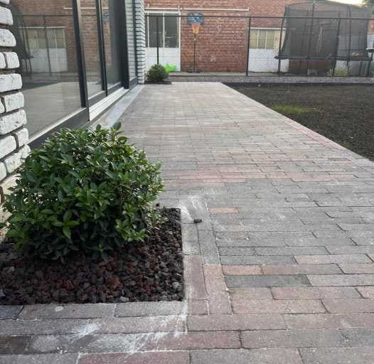 Aangelegd terras met plantenborder bij een woning
