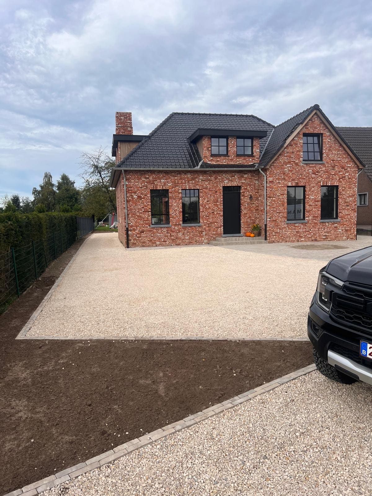 Afgewerkt tuinaanlegproject met grindoprit bij een woning in Hasselt